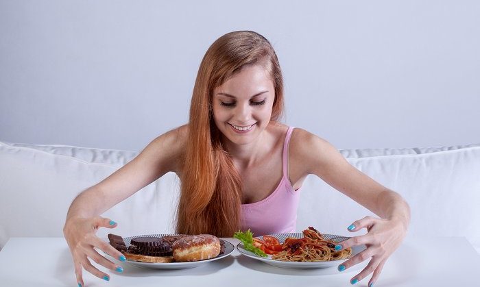 Young skinny girl binging on lots of food