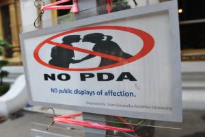 Heartbroken-a sign shows a man and women kissing-sign is crossed out with-the words NO PDA are written