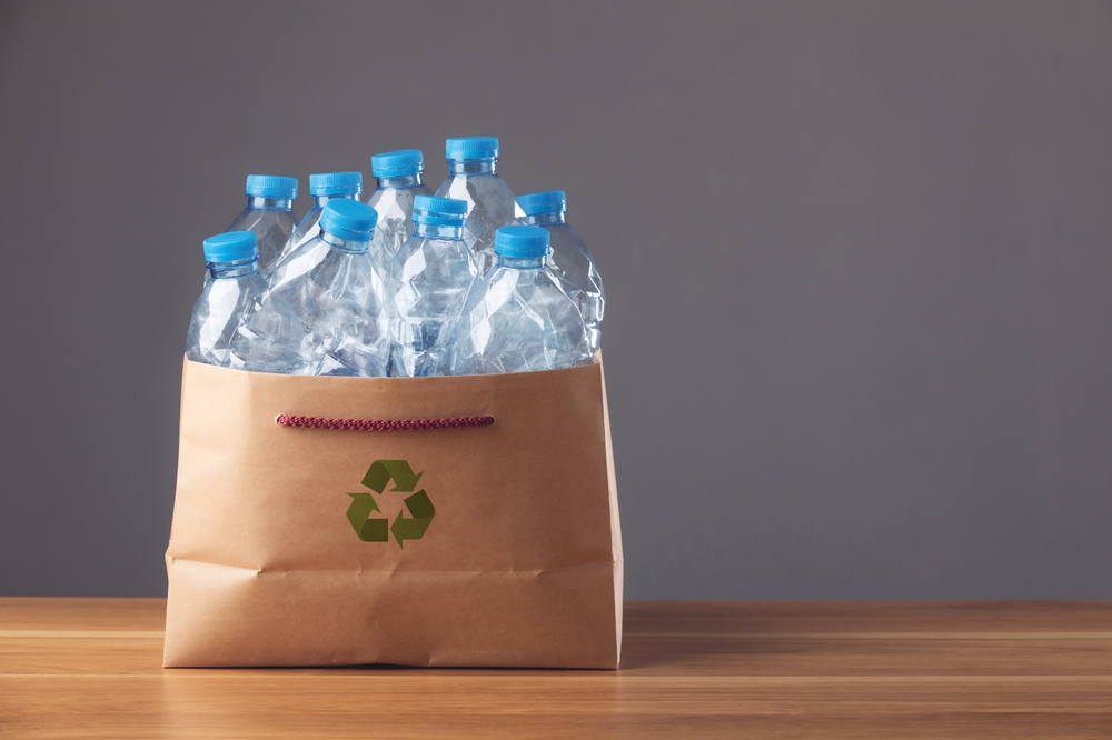 Save world and environment concept. Used blue plastic bottle in brown cardboard bag on wooden desk and dark background, Can use for reuse, recycle and environment concept. Studio shot.