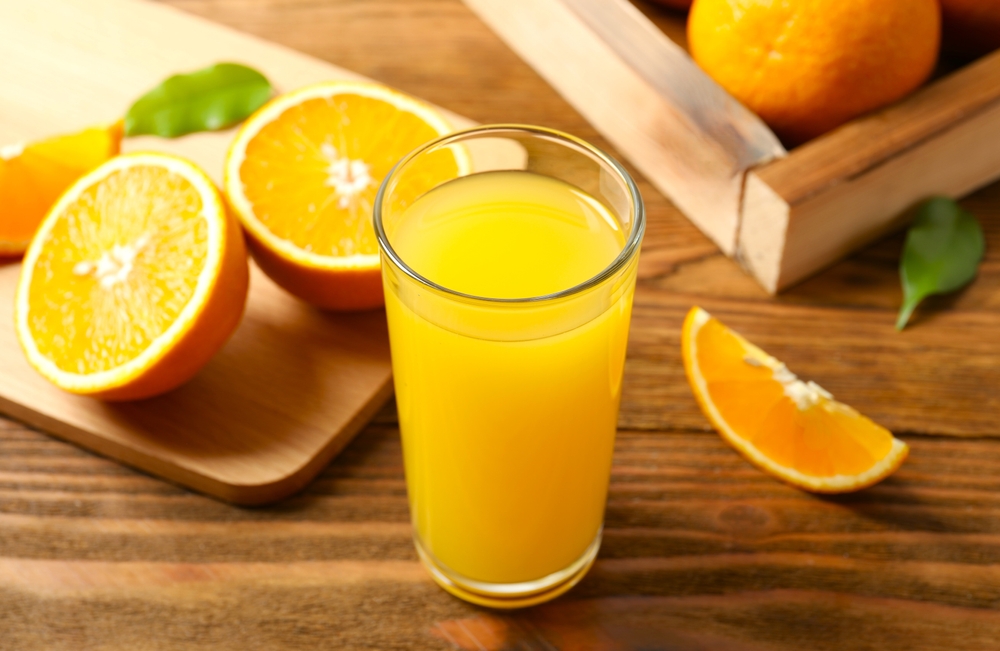 Glass of freshly squeezed orange juice on the table with citrus fruits