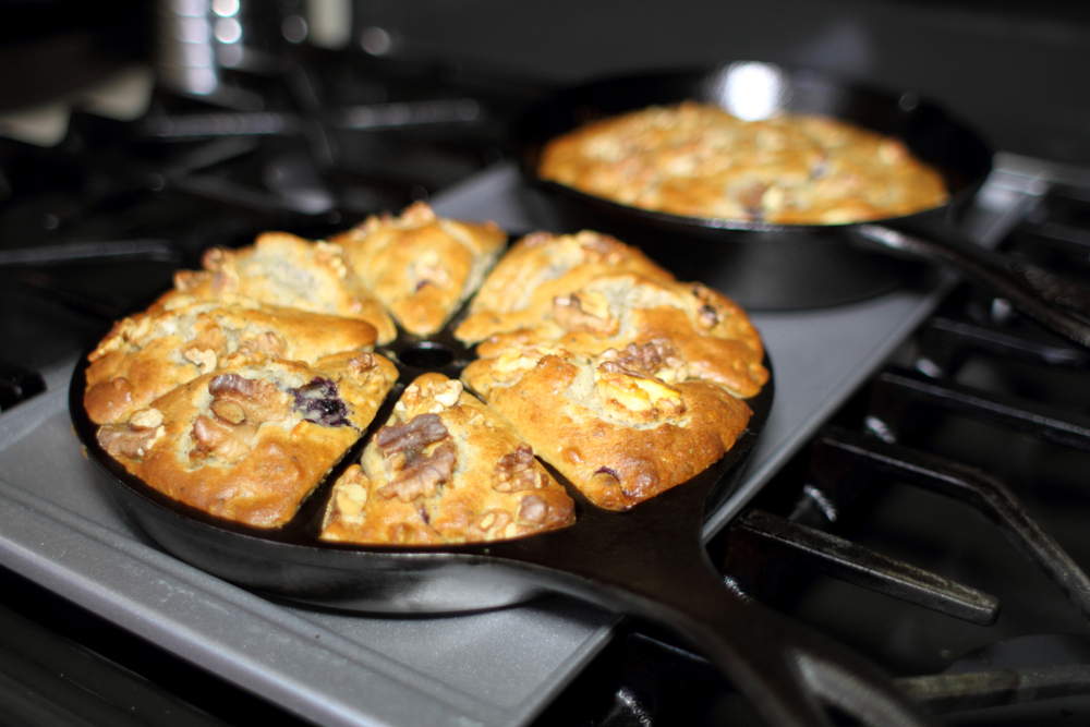 Banana nut bread with berries fresh out of the oven, baked in cast iron cookware in a home kitchen.