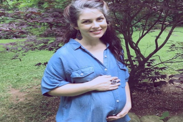 Pregnant woman smiling in a blue button up shirt