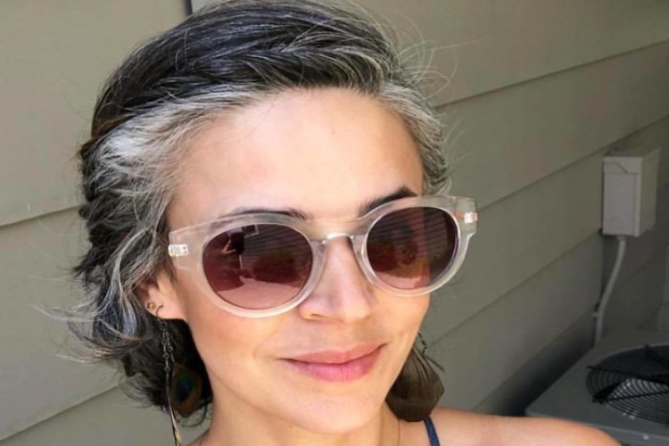 Woman with tied back salt and pepper hair and sunglasses