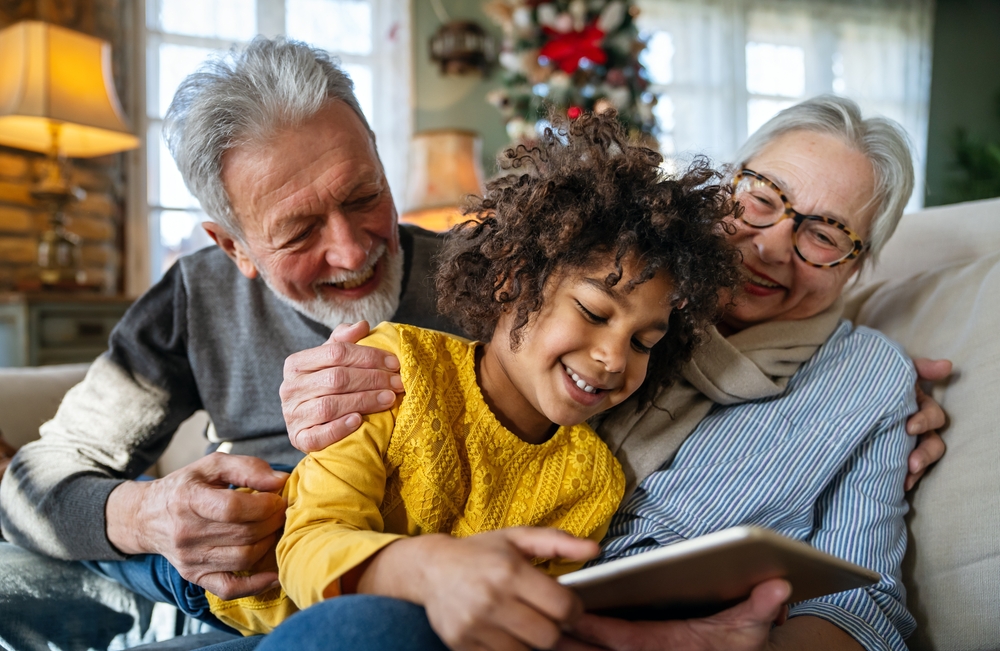 Portrait of happy grandparents with child playing together at home