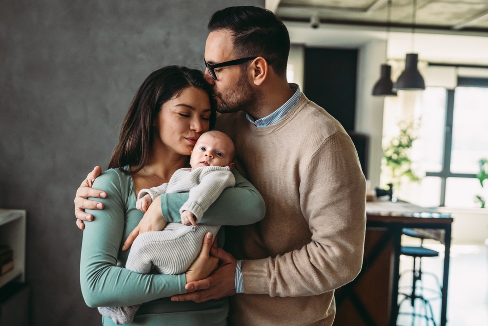 Portrait of parents and newborn baby. Father and mother kiss and hug a beautiful newborn child. .