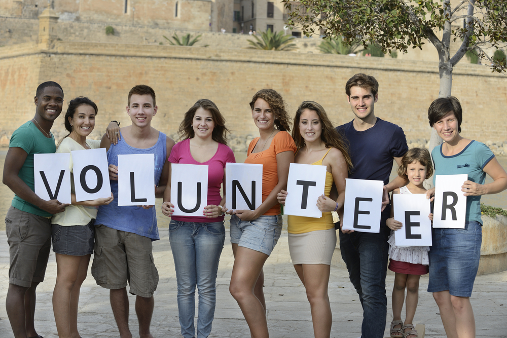 happy and diverse volunteer group holding sign
