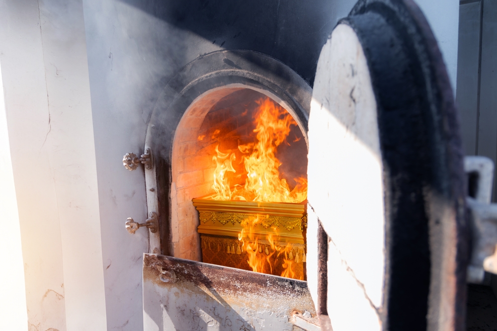 Crematorium door open with flame on coffin from cremate funeral human body cremation ceremony of religion buddhist in temple of Thailand.
