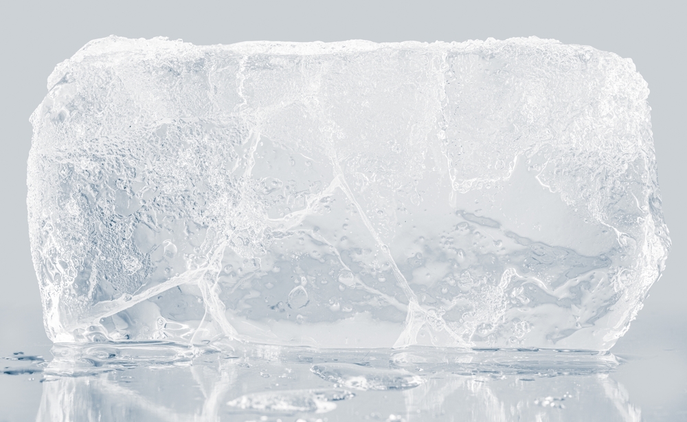 A textured block of transparent ice on a light gray background.
