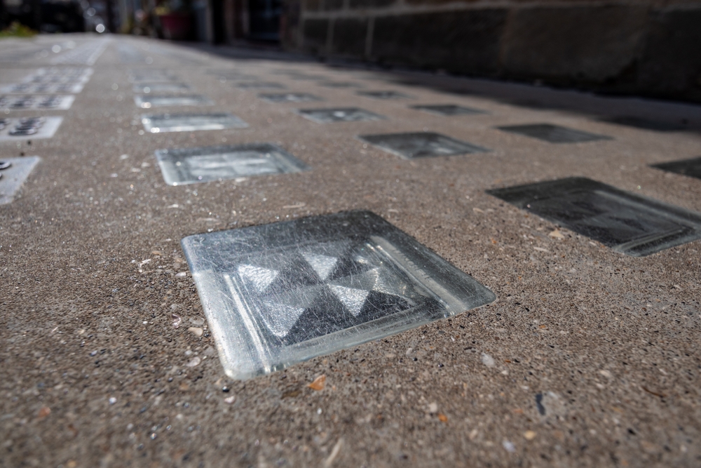 A set of translucent glass vault lights in a pavement above a basement area