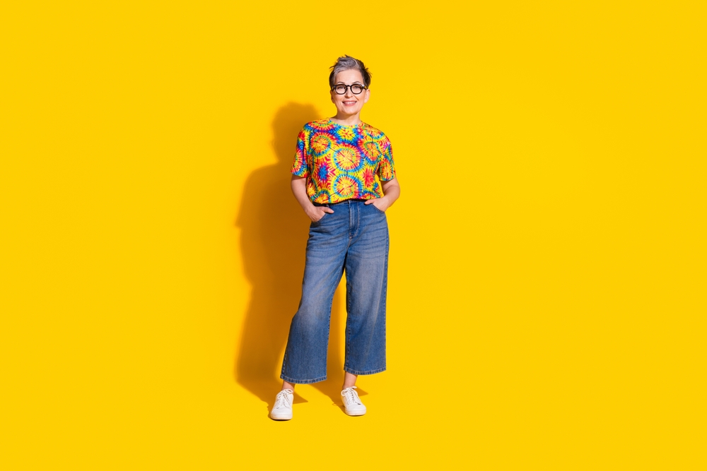 Photo of lovely senior woman wear stylish print clothes empty space isolated on vivid yellow color background
