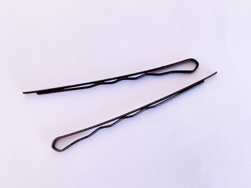 Top View of Black Bobby Pins Isolated on a White Background - Black Hairpins or Bobby Pins Against White Background
