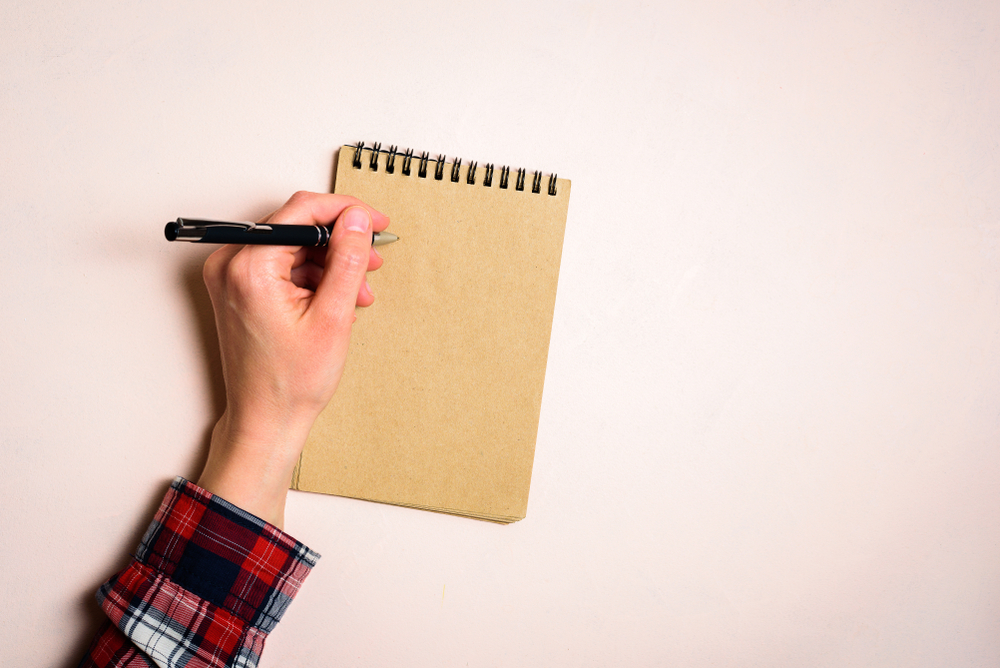 Man writing by left hand. Left hander day concept. Working place of lefty