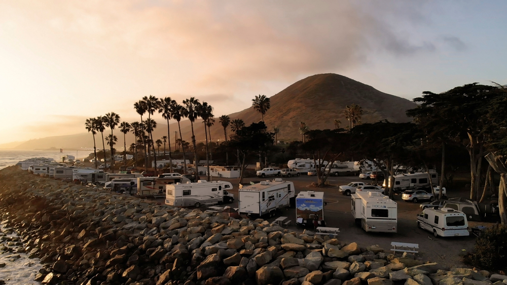 California, United States - July 9, 2018: RV park (campground) at coast, California. Ocean. California during sunset. Aerial view, from above, drone flying over water.