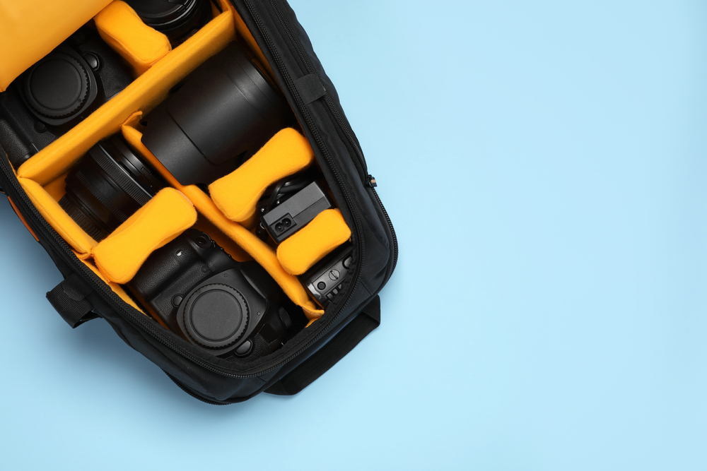 Professional photography equipment in backpack on turquoise background, top view. Space for text