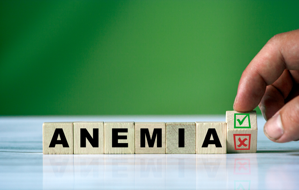 The hand turns the wooden cube and changes the word ANEMIA with green positive tick check box and red reject X check box.