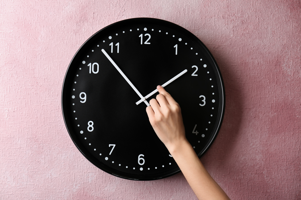 Woman changing time on big wall clock
