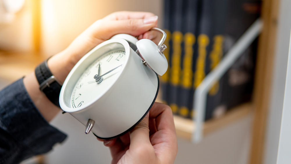 Male hand adjusting or changing the time on white clock. Time management concept.

