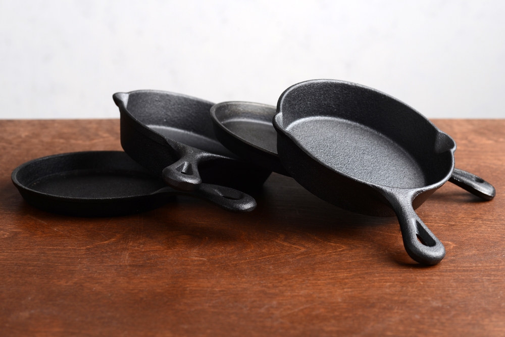 pile of cast iron skillets on old wood table