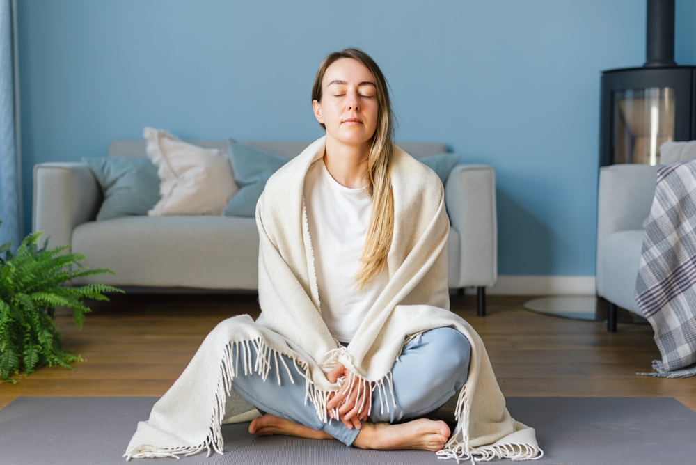 Young woman practicing meditation self care at home. Concept of mental health and women's wellness, mindfulness.