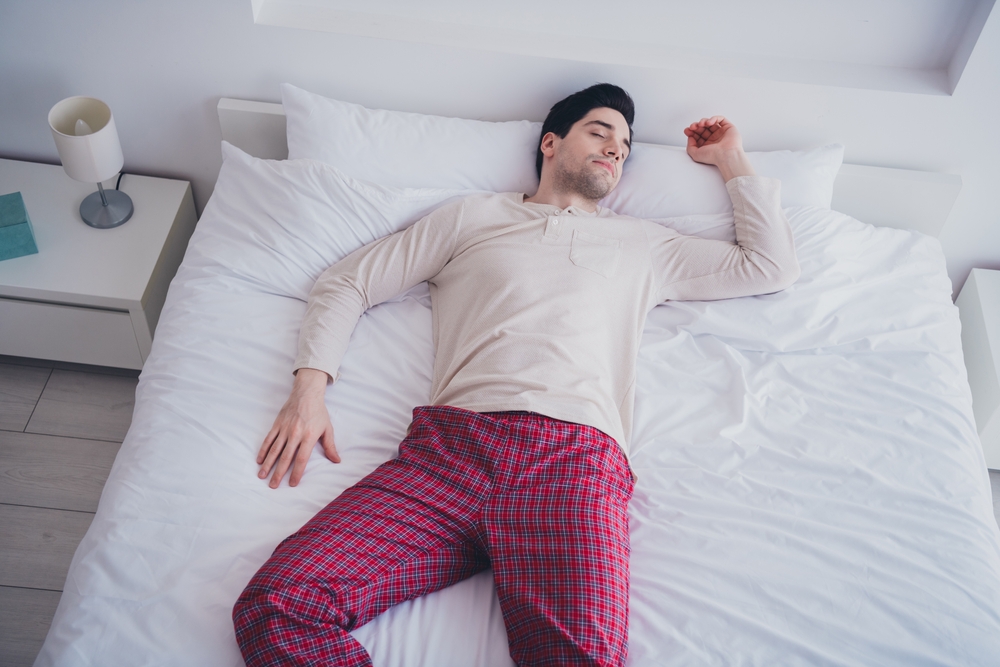 Photo of young attractive man peaceful sleeping lying in soft comfy bed white room interior inside