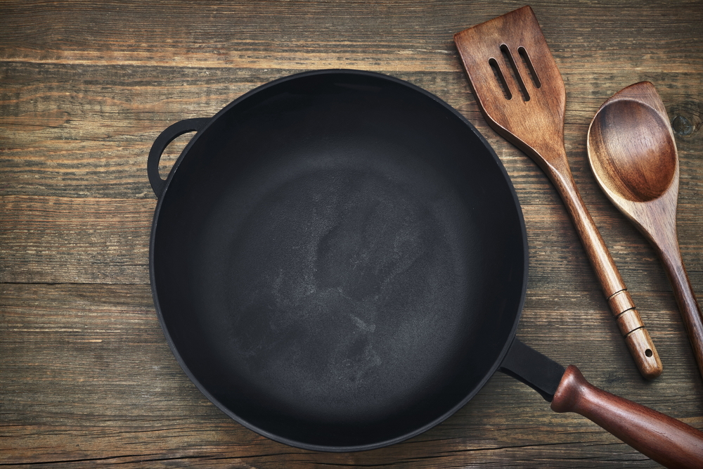 New Clean Empty Cast Iron Frying Pan And Spatula Top View On The Wooden Background