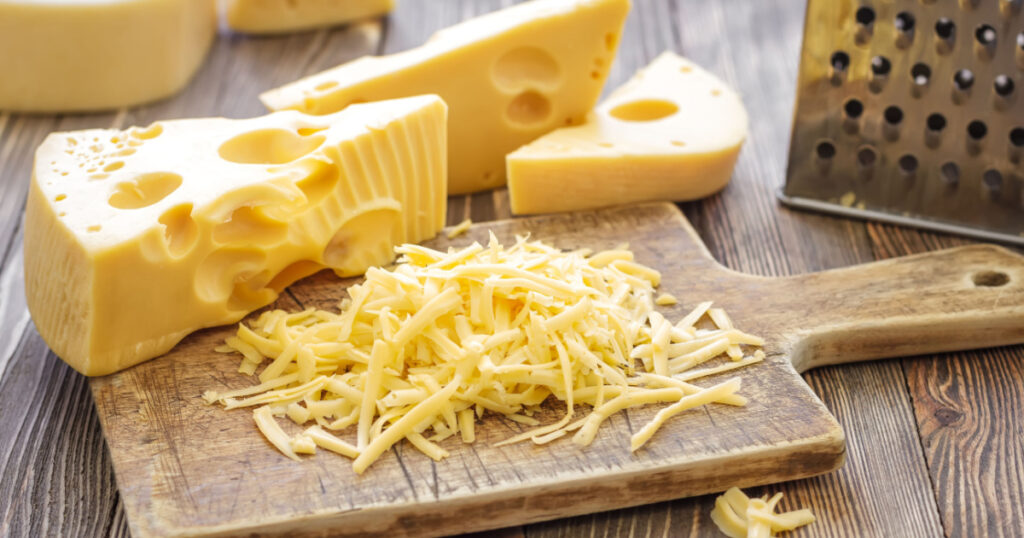 grated swiss cheese on wooden cutting board