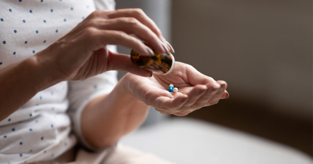 Close up 60s old woman pours out from bottle pills