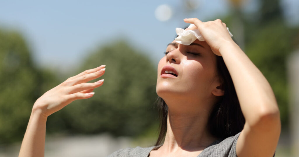 Stressed asian woman drying sweat with a cloth in a warm summer day