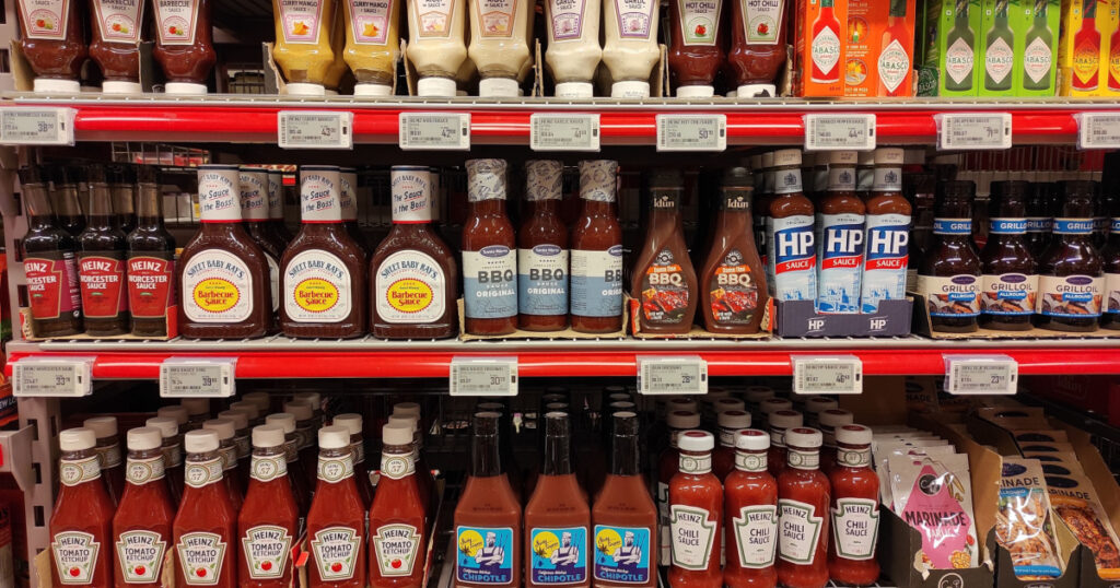 Barbecue chilli curry aioli ketchup and garlic sauces and dressings condiments glass container bottles in a shelf at the the grocery store high sodium and sugar