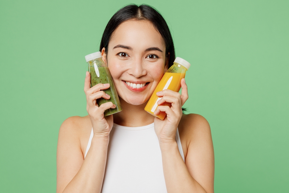 Young fun woan wear white clothes hold fruit juice yellow vegetable smoothie as detox diet isolated on plain pastel light green background. Proper nutrition healthy fast food unhealthy choice concept