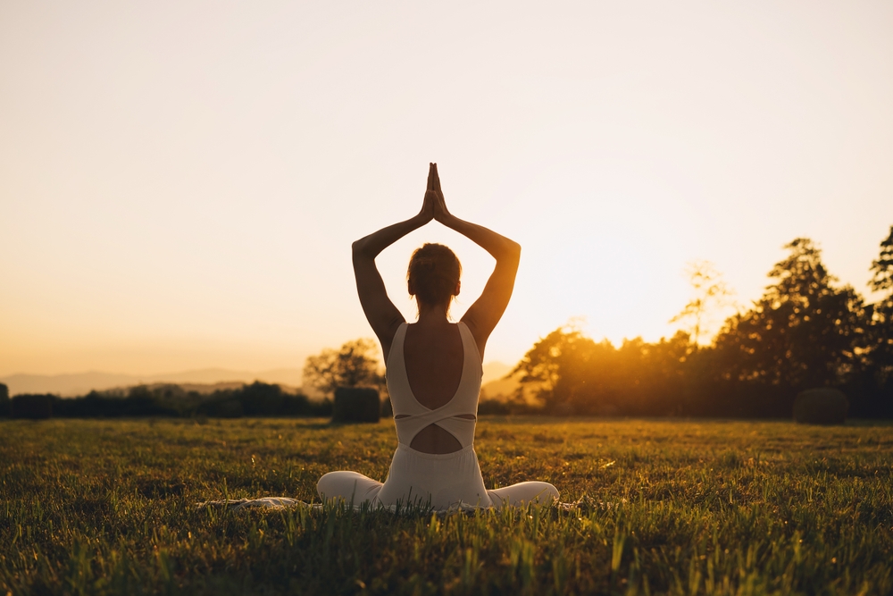 Young woman practicing yoga on nature. Girl meditating outdoors. Female with slim, strength and flexibility body. Healthy lifestyles. Concept of vitality, calmness, relax, mindfulness, zen energy.