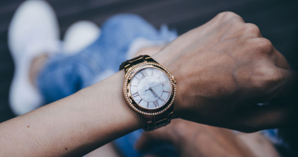 soft focus women in jean,white sneaker sitting outdoor on wooden floor background.looking at watch on hand, watching time. concept for punctuality, appointment