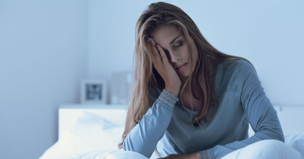Depressed woman awake in the night, she is touching her forehead