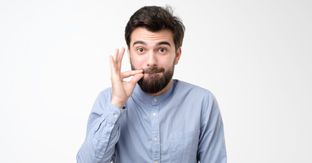  man in glasses, making gesture with hand, zipping lips, promising to keep secret