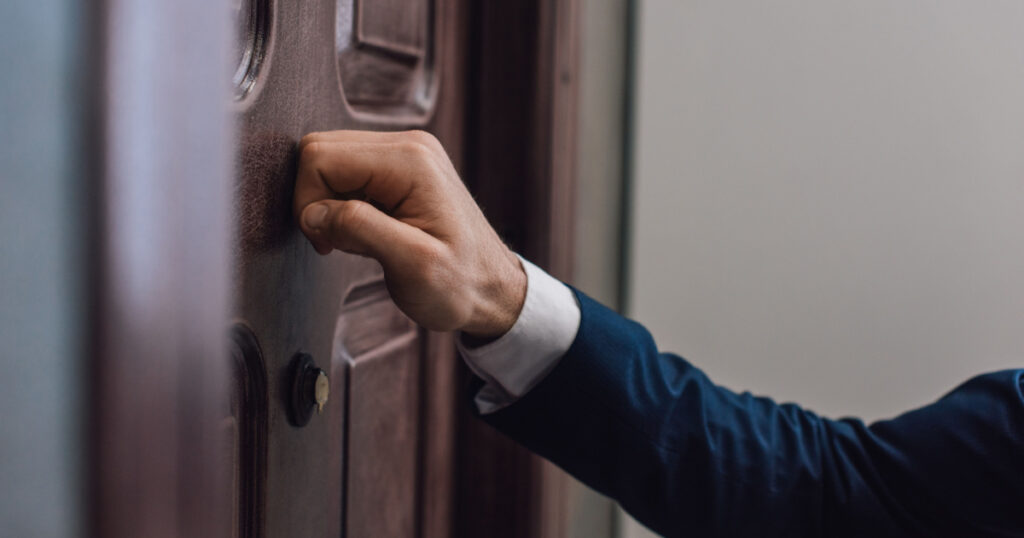Cropped view of collector knocking on door with hand
