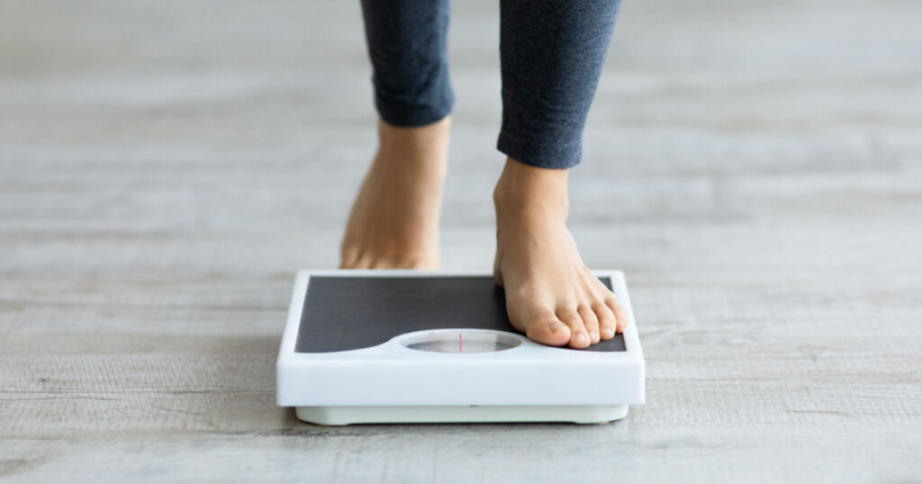 woman stepping on scales to measure her weight