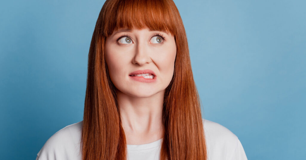 Photo of girl bite lip sorry guilty expression think isolated on blue background