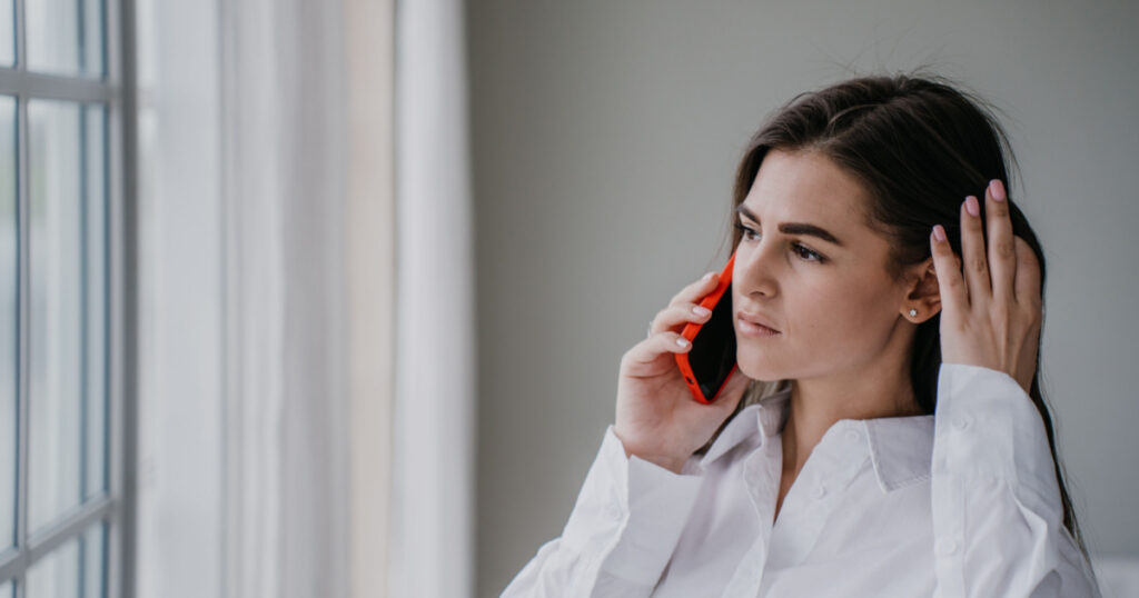 girl at home using cell phone looking hopelessly at window