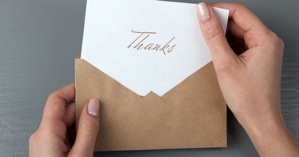 Women's hands with a letter in his hand with the words thank you