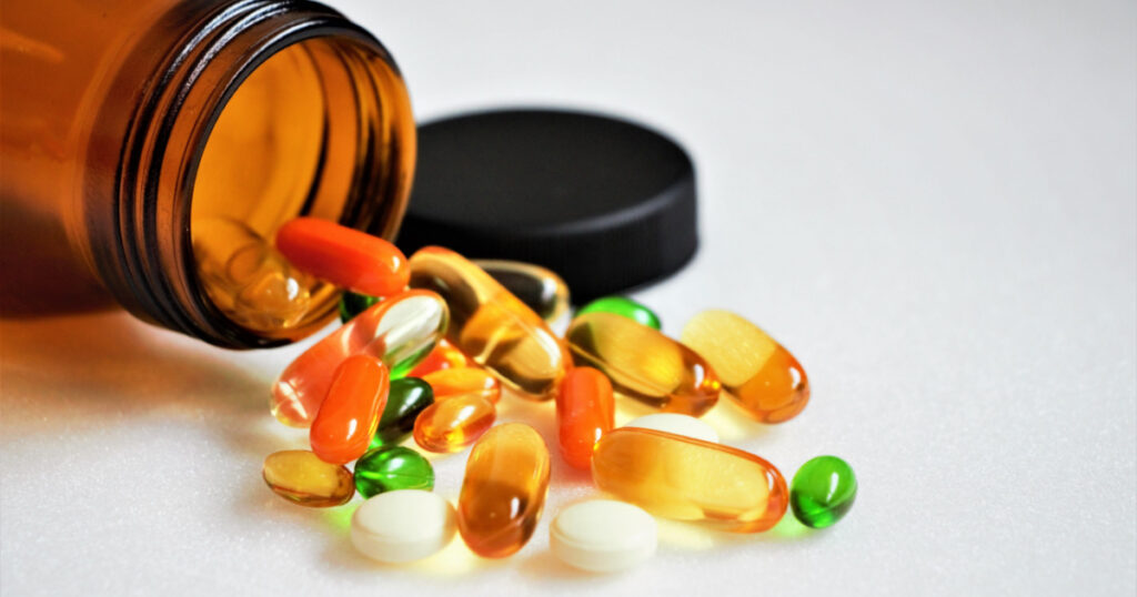 Close up vitamins and supplements on white background with a brown bottle. Including Vitamin c, vitamin E, vitamin D3, salmon oil, fish oil and co enzyme Q10 capsules.