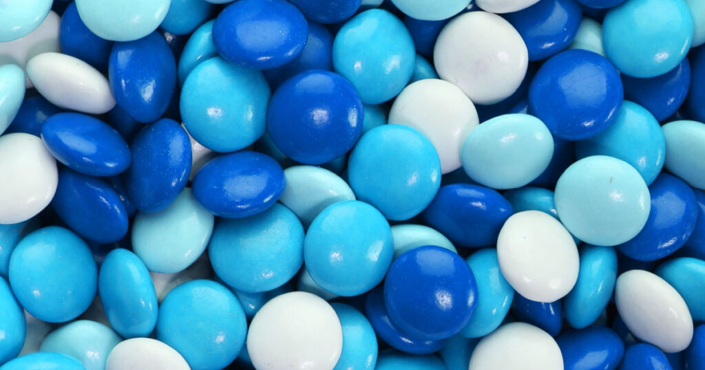 Chocolate candy coated in blue and white. Background