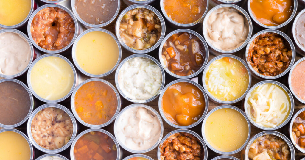 Colorful background of neatly arranged rows of opened cans of assorted soup viewed full frame from above in a food abstract still life