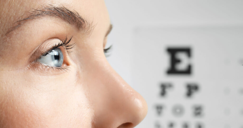 Young woman on eyesight test chart background