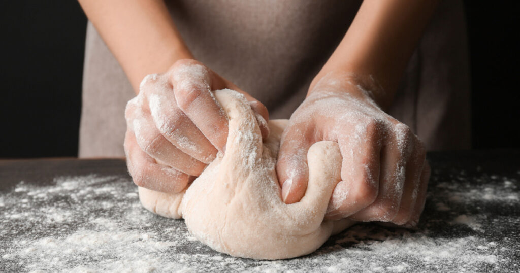 Female hands making dough for pizza