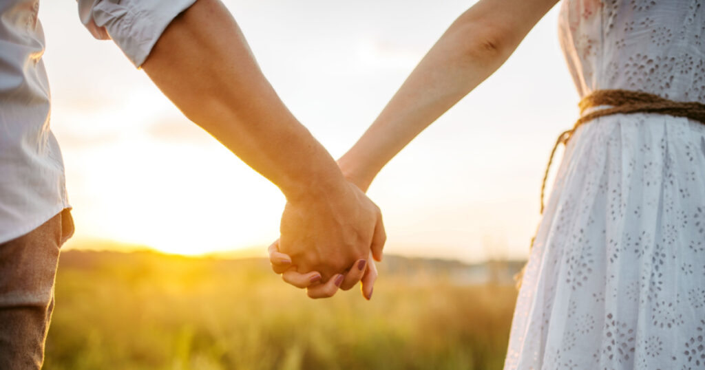 couple holding hands outside sunset