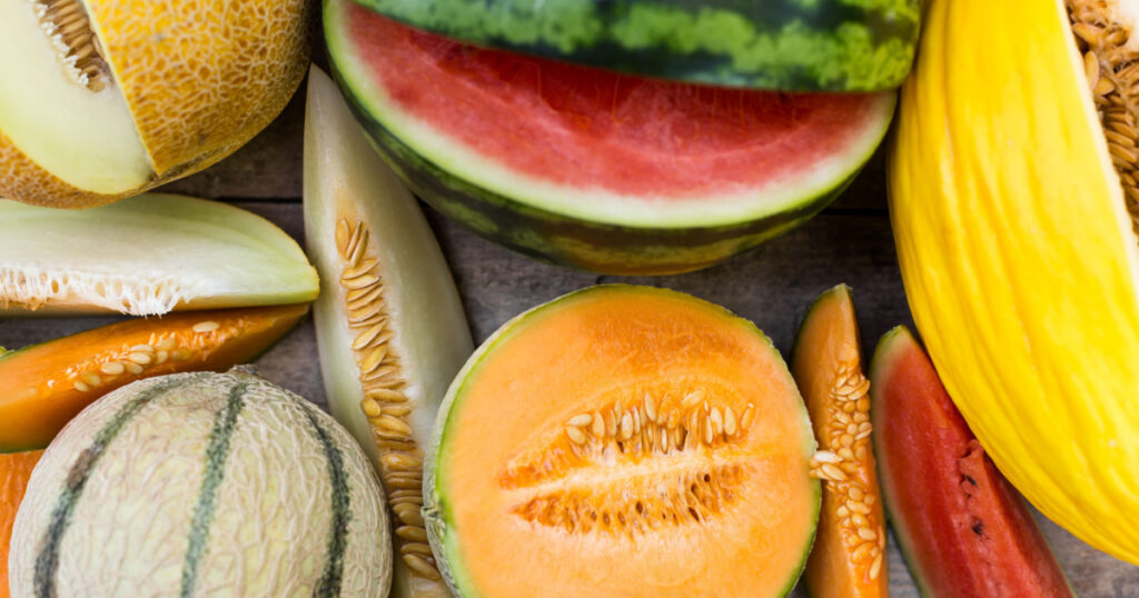 topview on a lot of different fresh melons, some are sliced, flat lay