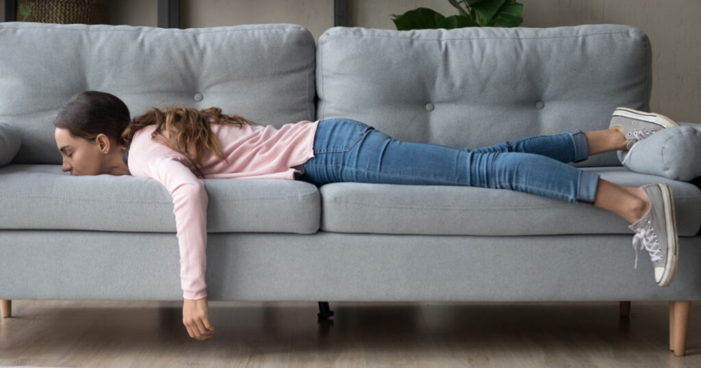 Full length of girl lying rest at home in living room buried her face in couch feels exhaustion having day nap lack of energy after party sleepless night or overworked, too tired no motivation concept