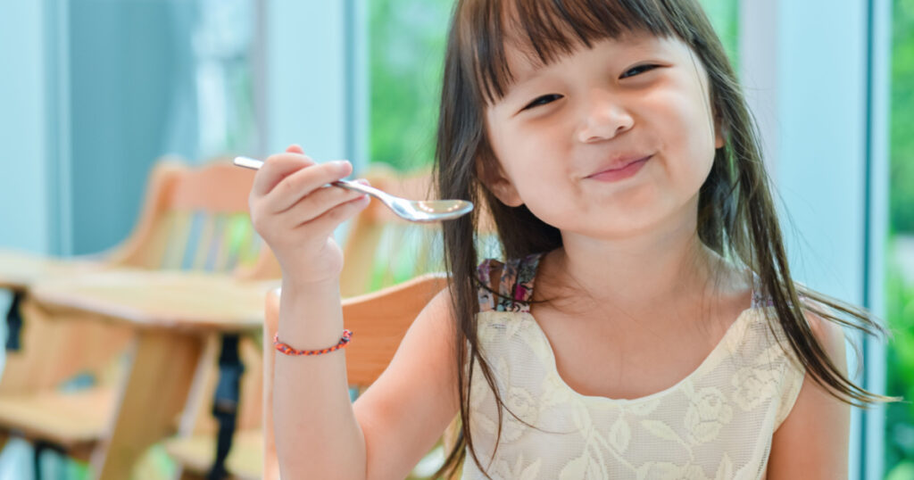 Little asian child girl having breakfast at the morning with a happy smiling face