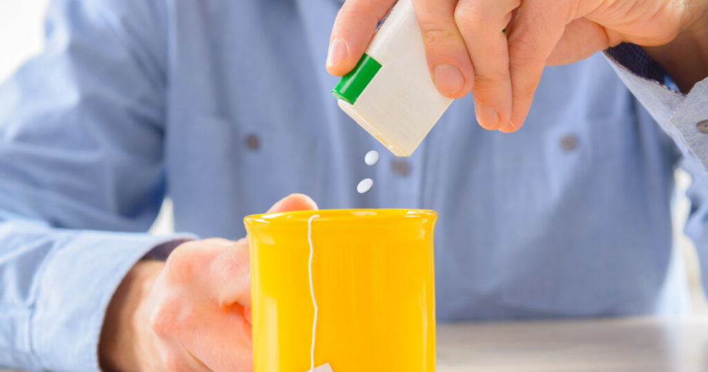 Sweetener tablets and hand with box whit cup of tea
