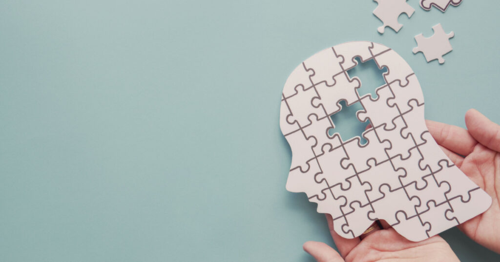 Hands holding brain with puzzle paper cutout, autism, memory loss, dementia, epilepsy and alzheimer awareness, world mental health day, world Parkinson day concept